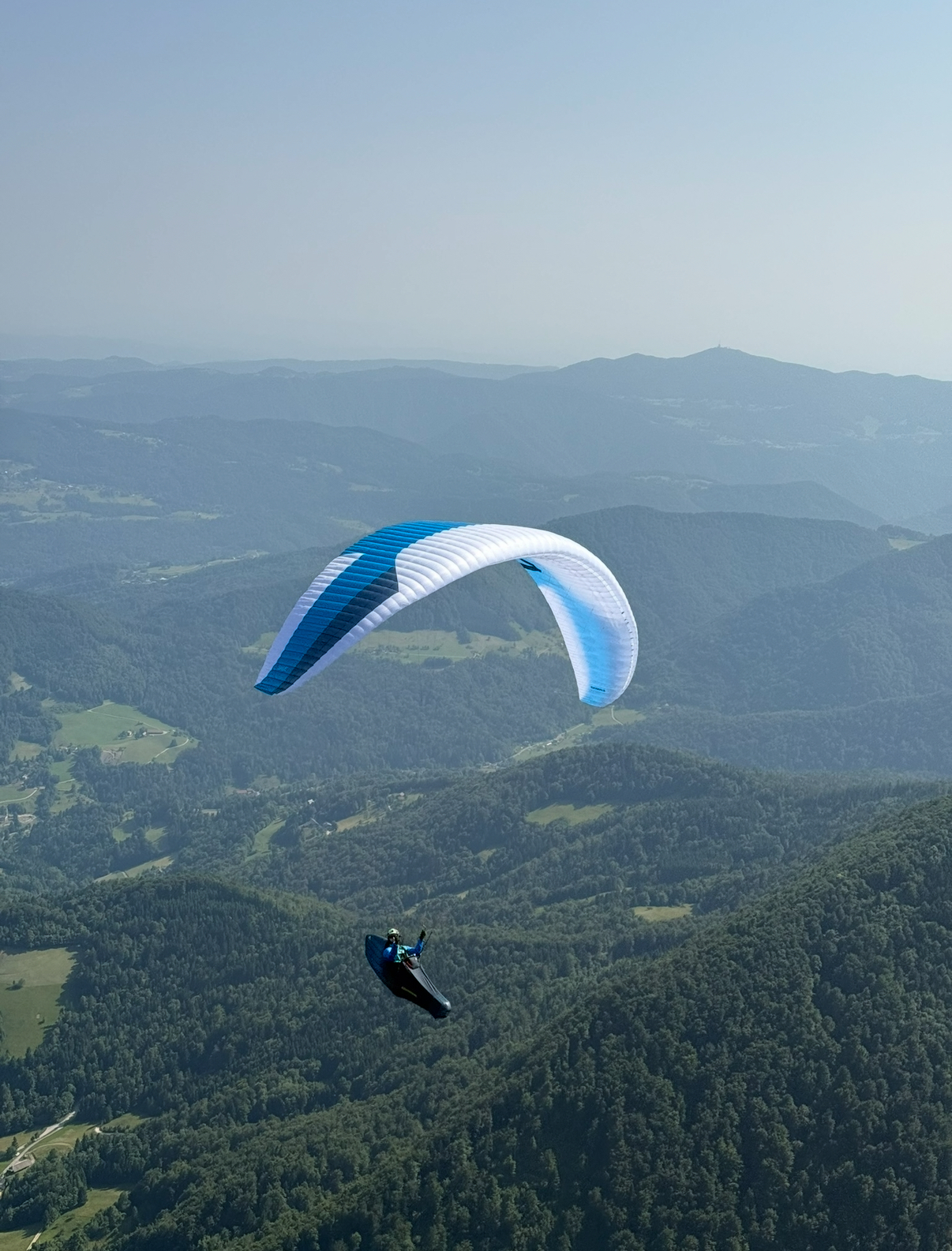 Paraglider above green hills in Slovenia