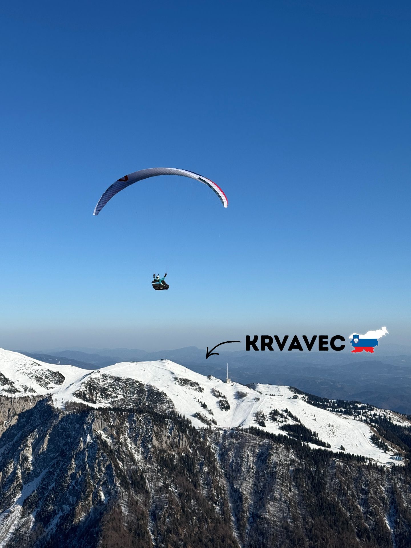 Paraglider above snowy Krvavec ridge